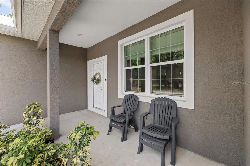 A covered front porch features a white door, a large window, and two dark chairs — 1311 W WASHINGTON STREET UNIT A, PLANT CITY, FL