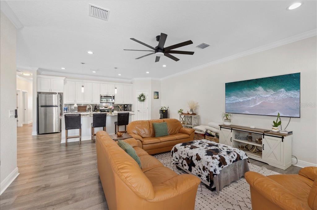 A living room with tan leather sofas, a cowhide ottoman, and an open-concept kitchen — 1311 W WASHINGTON STREET UNIT A, PLANT CITY, FL