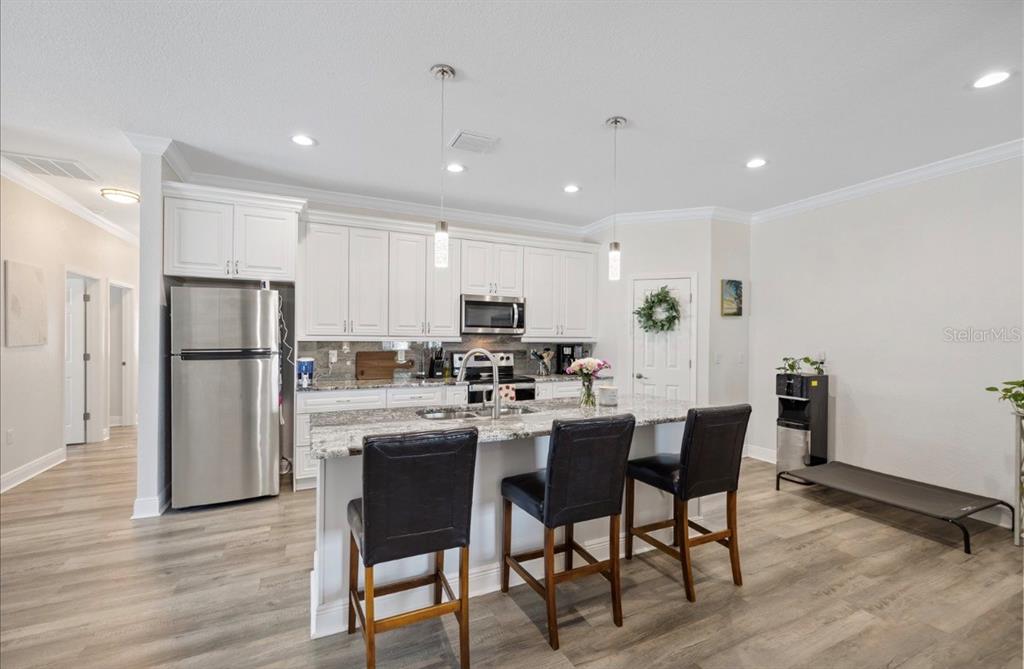 A kitchen features white cabinets, granite countertops, a center island with bar stools, and appliances — 1311 W WASHINGTON STREET UNIT A, PLANT CITY, FL