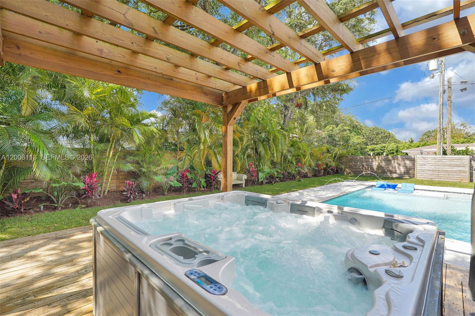 A hot tub sits on a wooden deck under a pergola next to a pool — 2 NW 89th St, El Portal FL 33150, EL PORTAL, FL