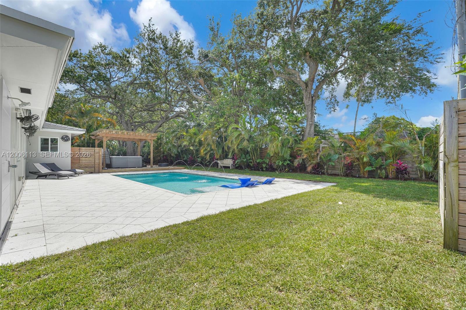 A backyard features a swimming pool, a patio, a wooden pergola, and lush landscaping — 2 NW 89th St, El Portal FL 33150, EL PORTAL, FL