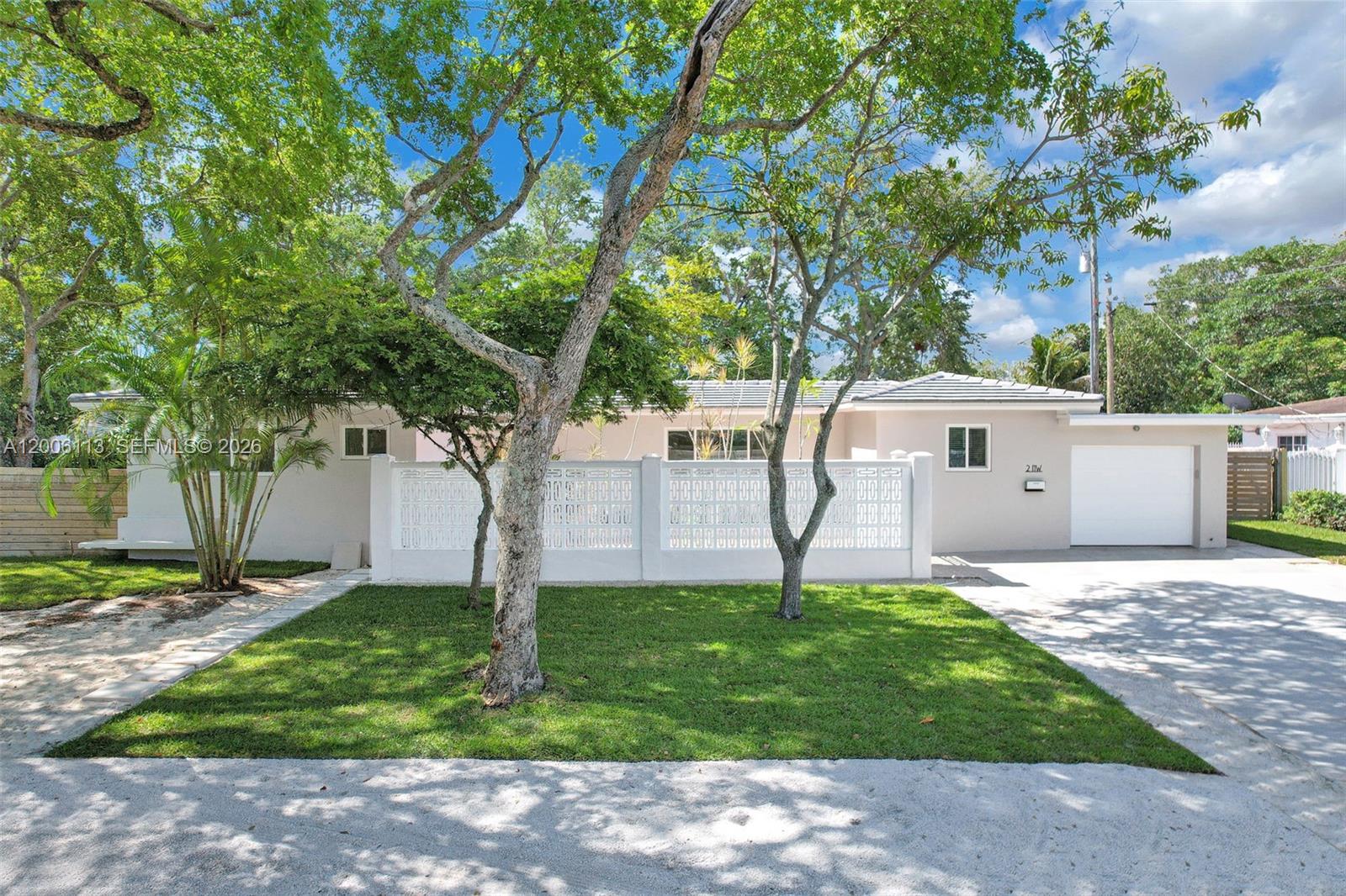A single-story house with a white decorative fence, a front lawn, and a garage — 2 NW 89th St, El Portal FL 33150, EL PORTAL, FL