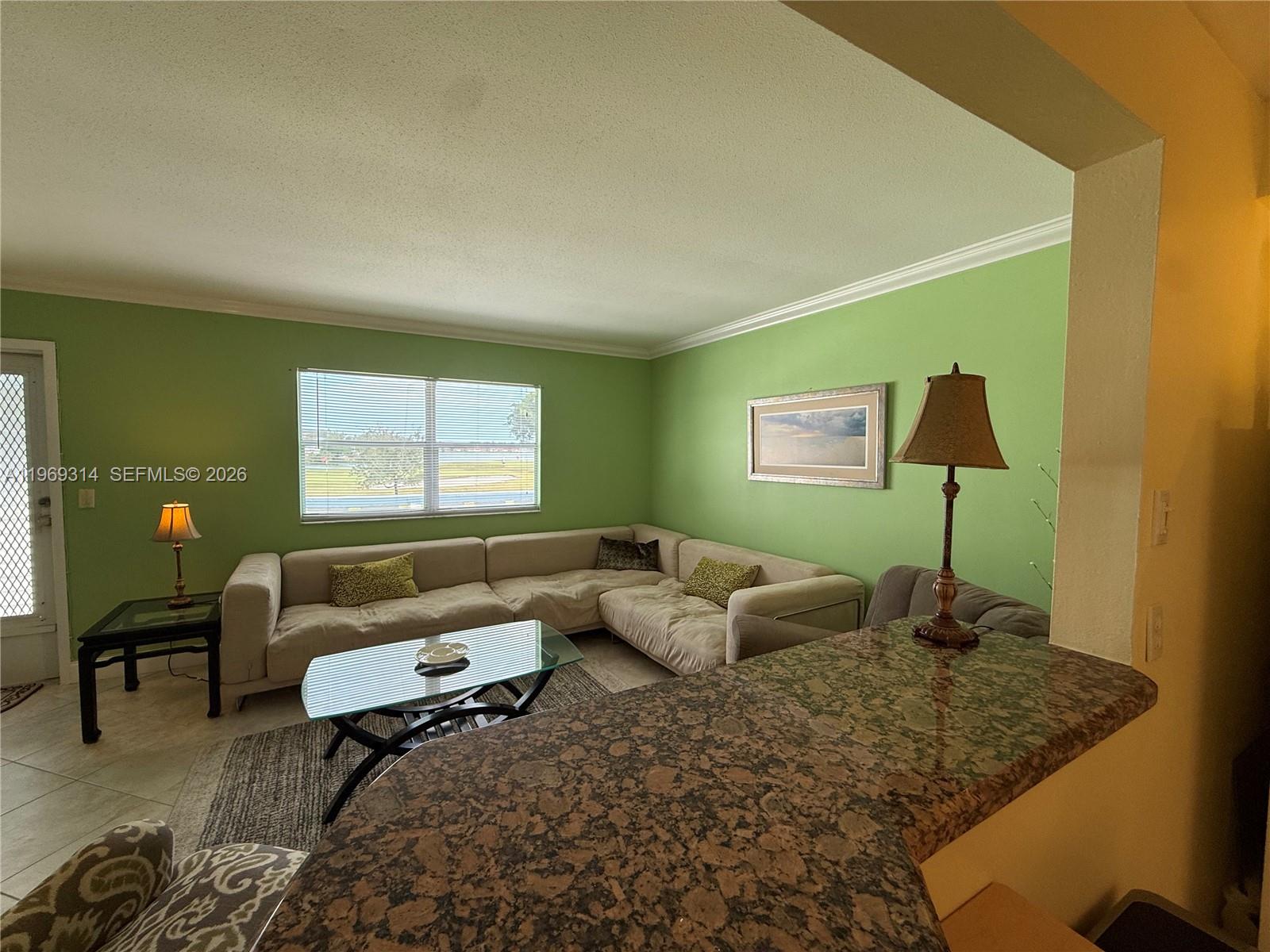 A living room features green walls, a large sectional sofa, and a granite-topped breakfast bar — 127 Tuscany B # 127, Delray Beach FL 33446, DELRAY BEACH, FL