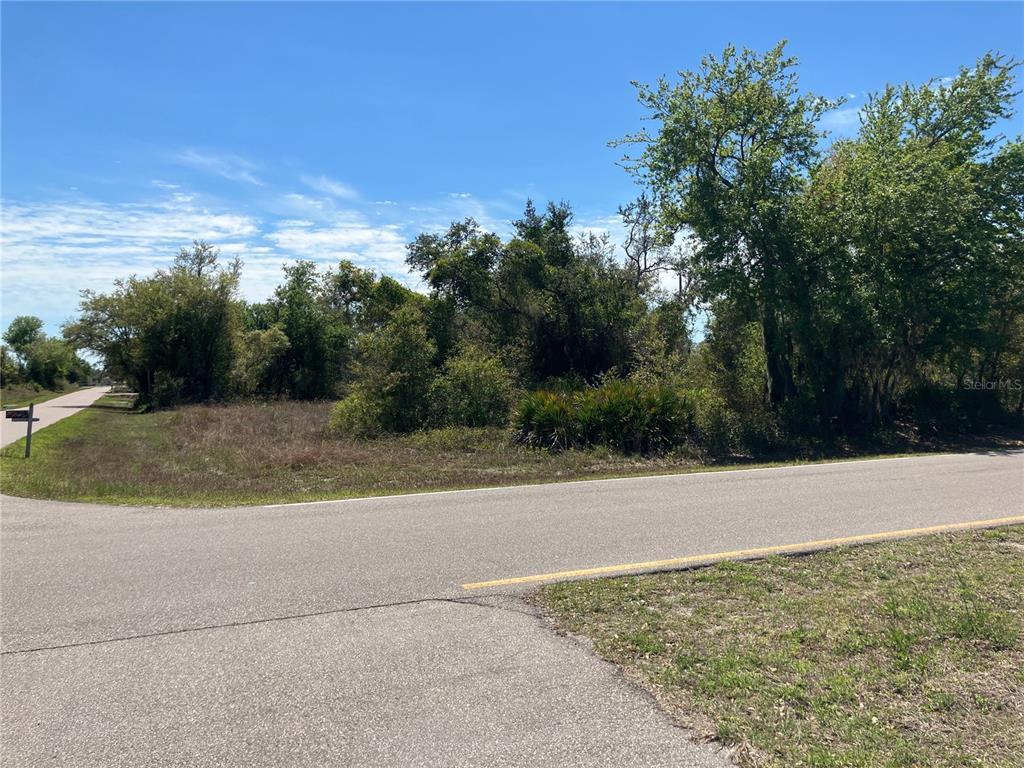 A vacant, wooded corner lot sits at the intersection of two paved roads — 273 OMEN STREET, PUNTA GORDA, FL