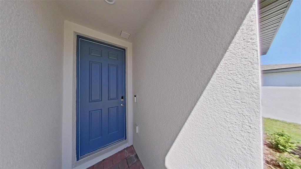 A blue front door is set within a recessed entryway with white stucco walls — 2404 WHITE TAIL STREET, DAVENPORT, FL
