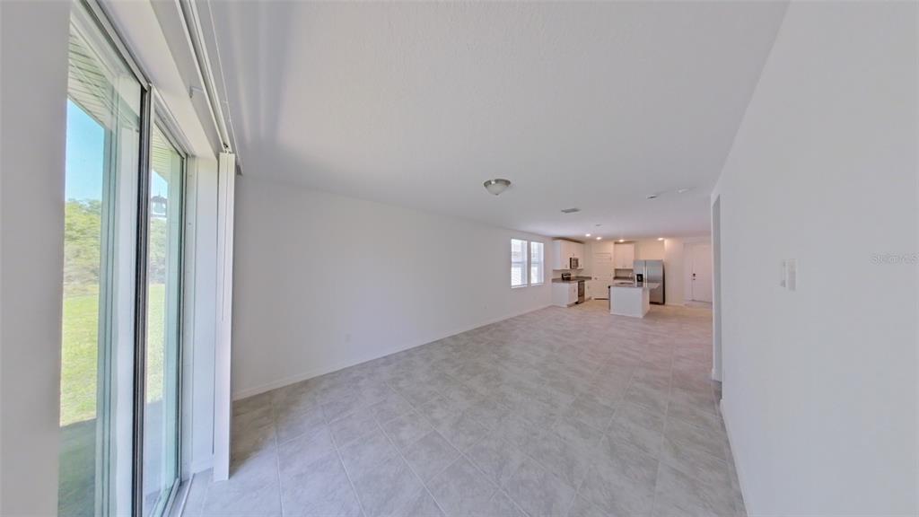 An open-concept living area with light tile flooring leads to a kitchen with white cabinets — 2404 WHITE TAIL STREET, DAVENPORT, FL
