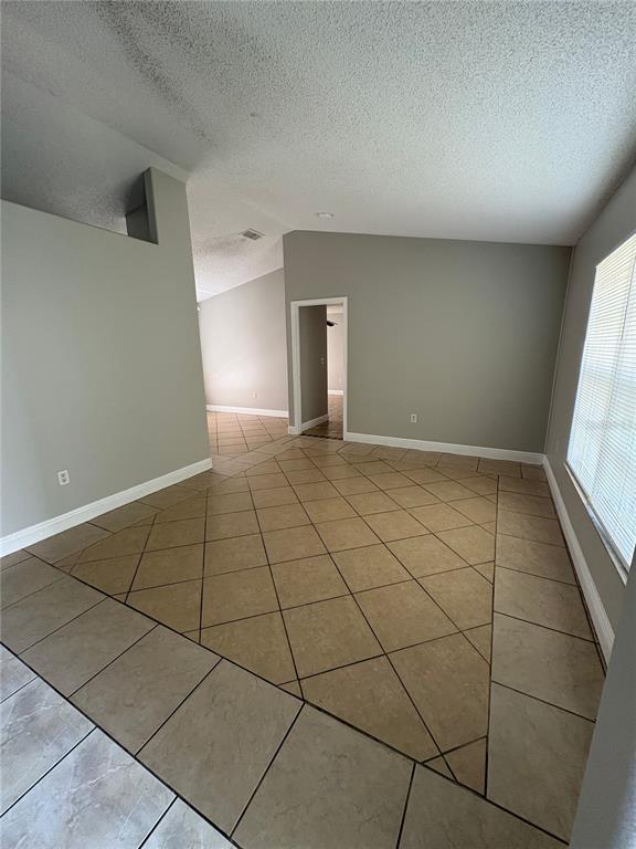 A living room features a gray area rug, beige furniture, and a glass coffee table — 305 COLONADE COURT, KISSIMMEE, FL