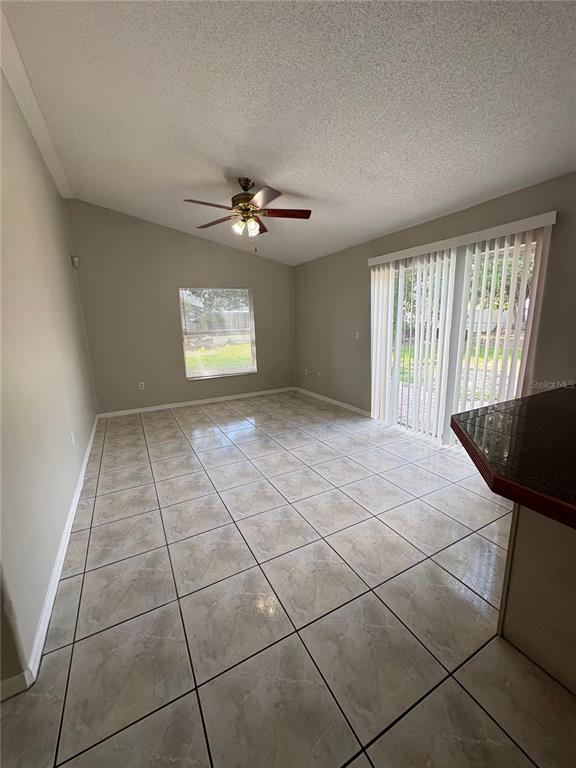 An interior room features light gray walls, a vaulted ceiling, and diagonal tan floor tiles — 305 COLONADE COURT, KISSIMMEE, FL
