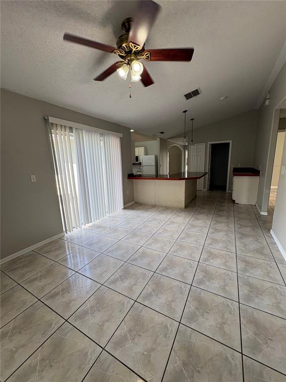 A dining room features a glass table, six chairs, a rug, and sliding glass doors — 305 COLONADE COURT, KISSIMMEE, FL