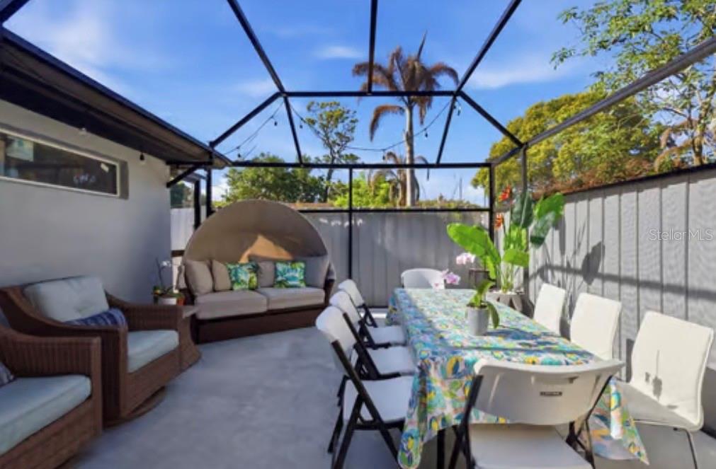A screened-in patio features a dining table, wicker seating, and a large semi-circular outdoor sofa — 1046 MORRIS AVENUE UNIT 1046, ORLANDO, FL