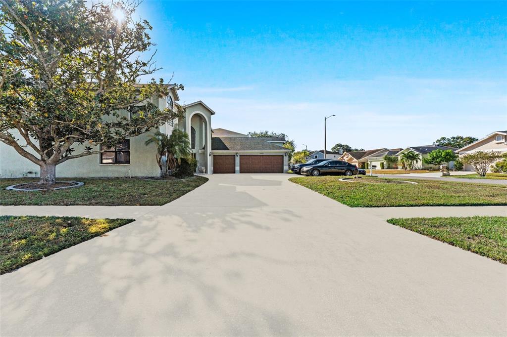 A two-story house with a large concrete driveway and a three-car garage — 11429 ZENITH CIRCLE, TAMPA, FL