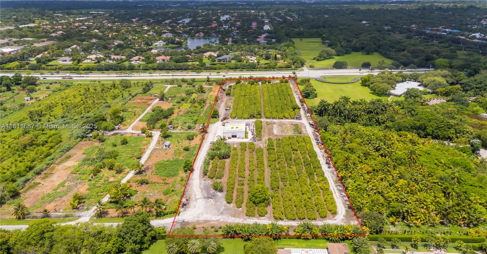 An aerial view shows a rectangular agricultural property featuring rows of trees and a building — 4077 SW 121st Ter, Davie FL 33330, DAVIE, FL