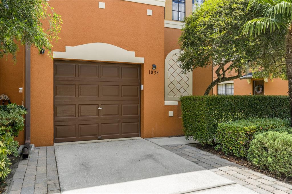 A brown garage door is set into an orange stucco exterior with a concrete driveway — 1033 BLACKWATER DRIVE, WESLEY CHAPEL, FL