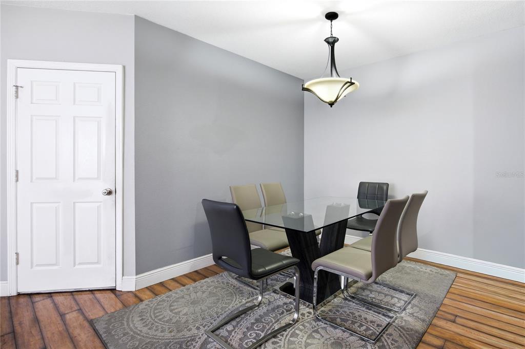 A dining room features a glass-topped table, six chairs, a patterned rug, and a chandelier — 1033 BLACKWATER DRIVE, WESLEY CHAPEL, FL