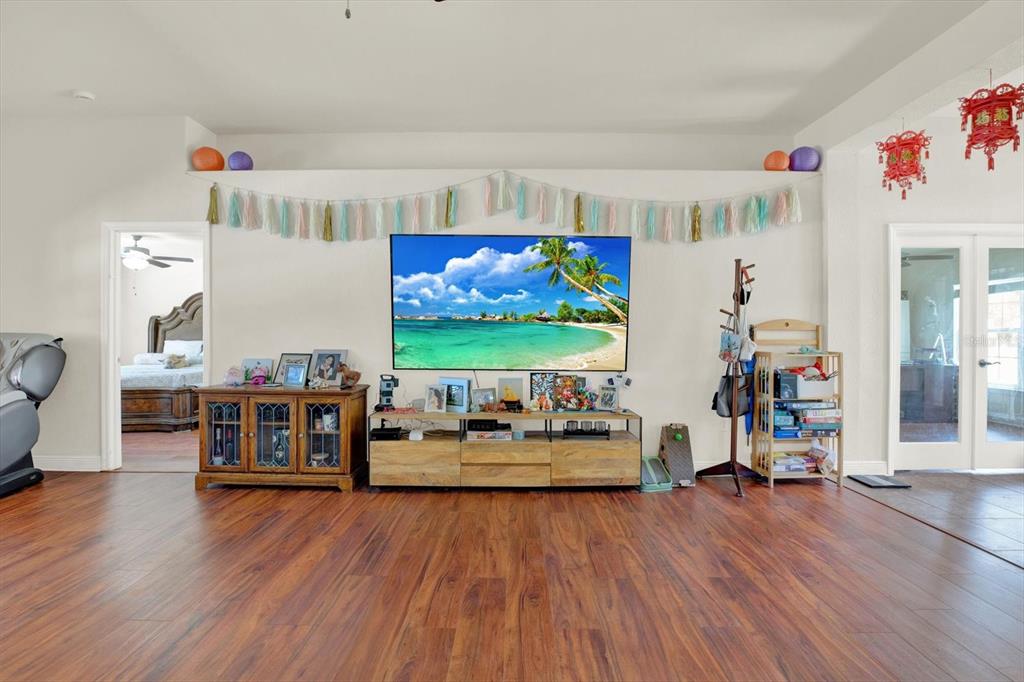 A living room features wood-look flooring, a wall-mounted television, and a wooden media console — 14061 WHITE PLAINS STREET, SPRING HILL, FL