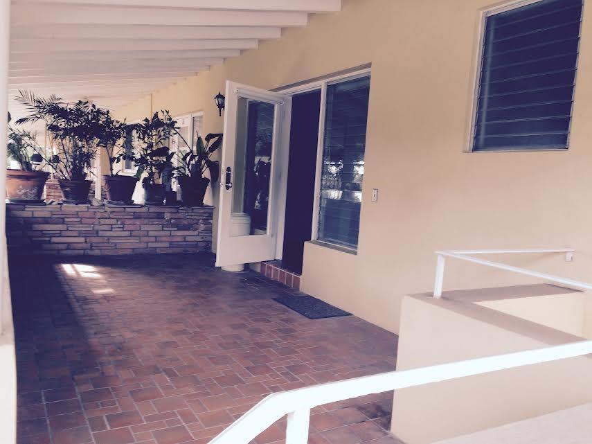 A covered patio features brick flooring, potted plants, and a white door leading inside — 30 Park Drive # 15, Bal Harbour FL 33154, BAL HARBOUR, FL