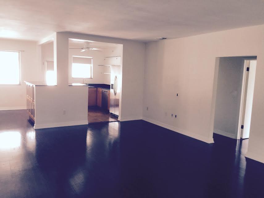 An open-concept living area features dark hardwood floors, white walls, and an adjacent kitchen — 30 Park Drive # 15, Bal Harbour FL 33154, BAL HARBOUR, FL