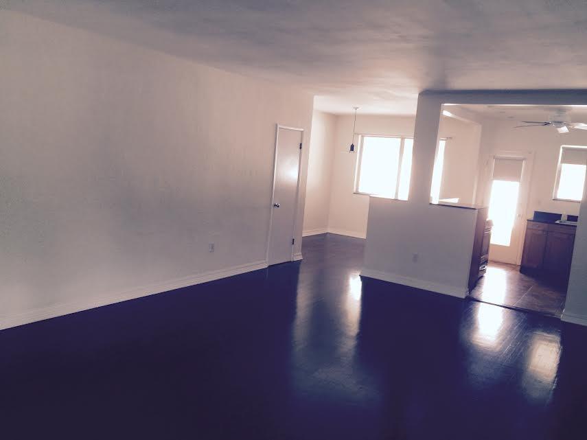 An open-concept living area features dark hardwood floors, white walls, and a kitchen beyond — 30 Park Drive # 15, Bal Harbour FL 33154, BAL HARBOUR, FL