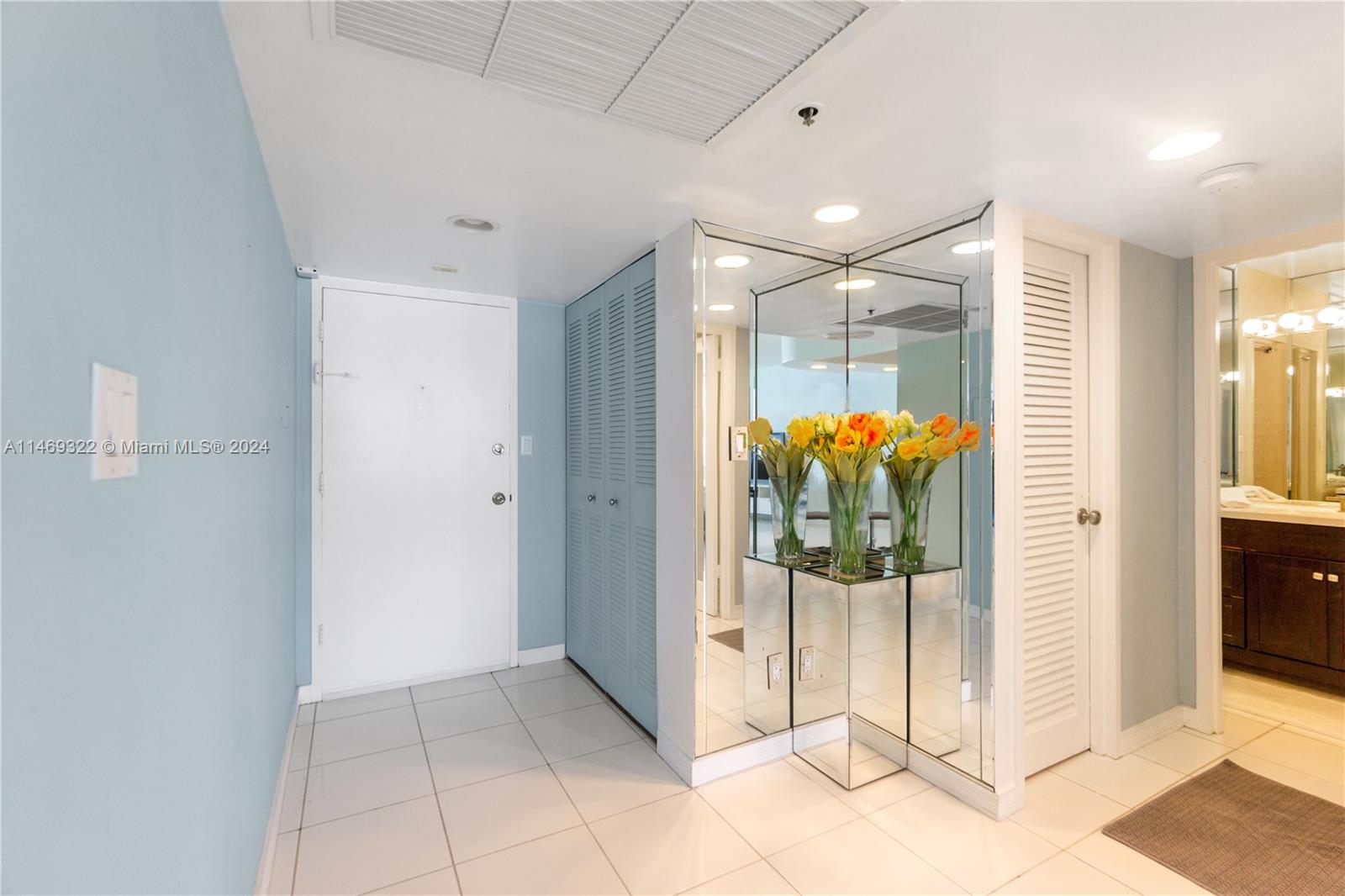 An entryway features light blue walls, white tile flooring, a mirrored console, and louvered doors — 100 Lincoln Rd # 1043, Miami Beach FL 33139, MIAMI BEACH, FL