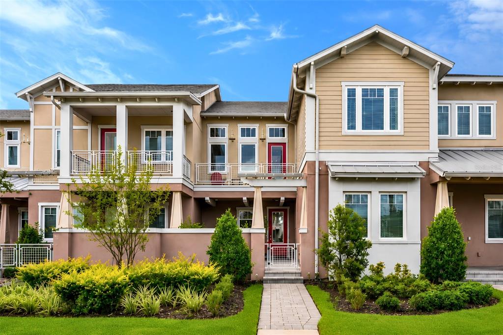 A two-story townhouse exterior with a tan facade, red doors, and a front walkway — 13851 SCHROCK AVENUE, ORLANDO, FL