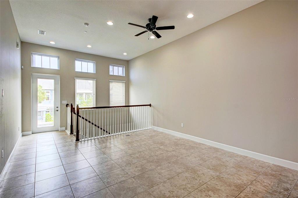 A tiled loft area features a ceiling fan, large windows, and a staircase railing — 13851 SCHROCK AVENUE, ORLANDO, FL