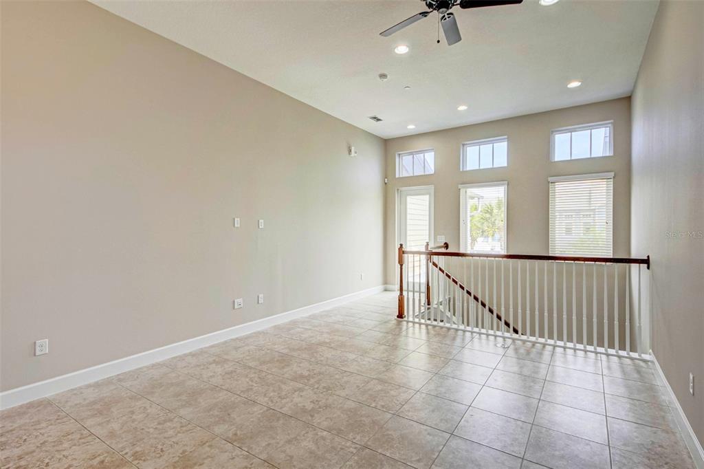 A spacious room with tile flooring, high ceilings, a ceiling fan, and a staircase railing — 13851 SCHROCK AVENUE, ORLANDO, FL