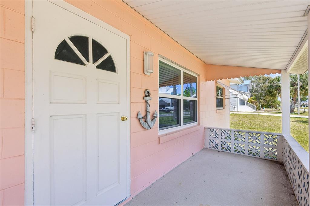 A pink concrete block house features a white front door and a decorative anchor — 3303 MINNOW CREEK DRIVE, HERNANDO BEACH, FL