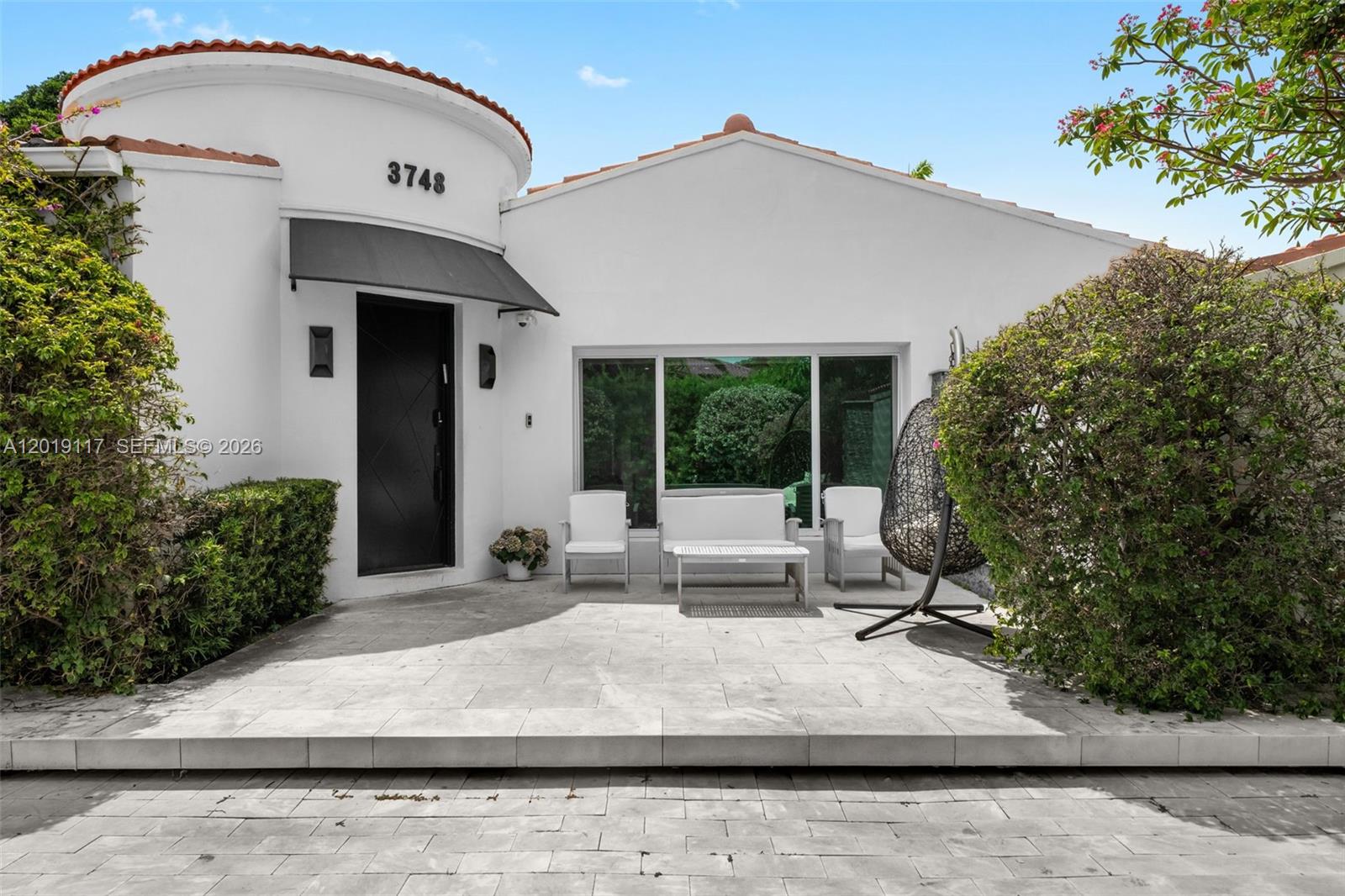 The exterior of a white house features a circular entrance, a patio, and outdoor furniture — 3748 Prairie Ave, Miami Beach FL 33140, MIAMI BEACH, FL