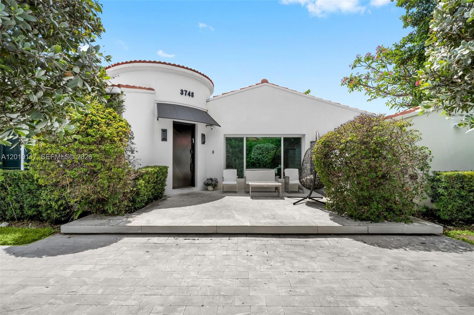 The exterior of a white house features a circular entryway, a patio, and landscaping — 3748 Prairie Ave, Miami Beach FL 33140, MIAMI BEACH, FL