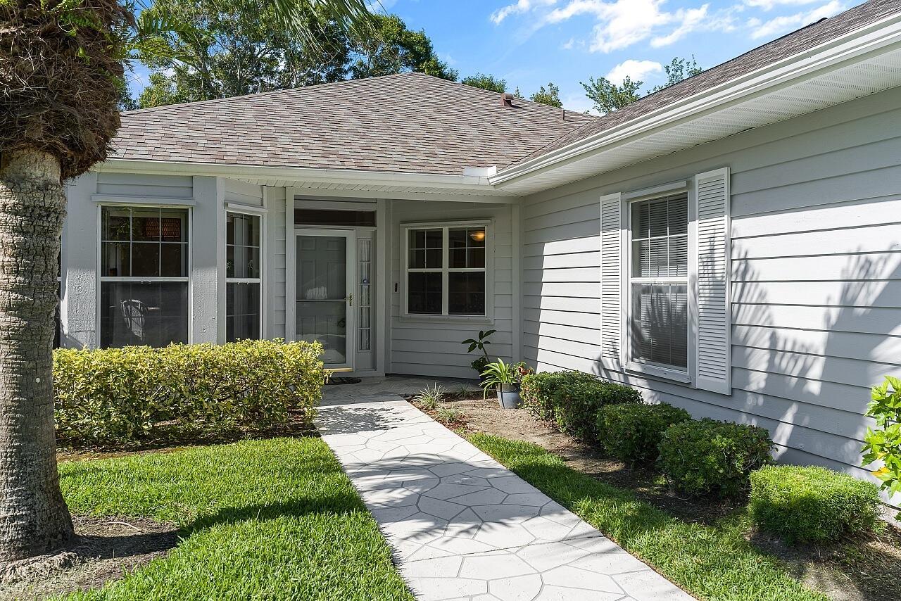 A gray-sided house features a stone-patterned walkway leading to a recessed front entrance — 431 Tamarind Place, Vero Beach FL 32962, VERO BEACH, FL