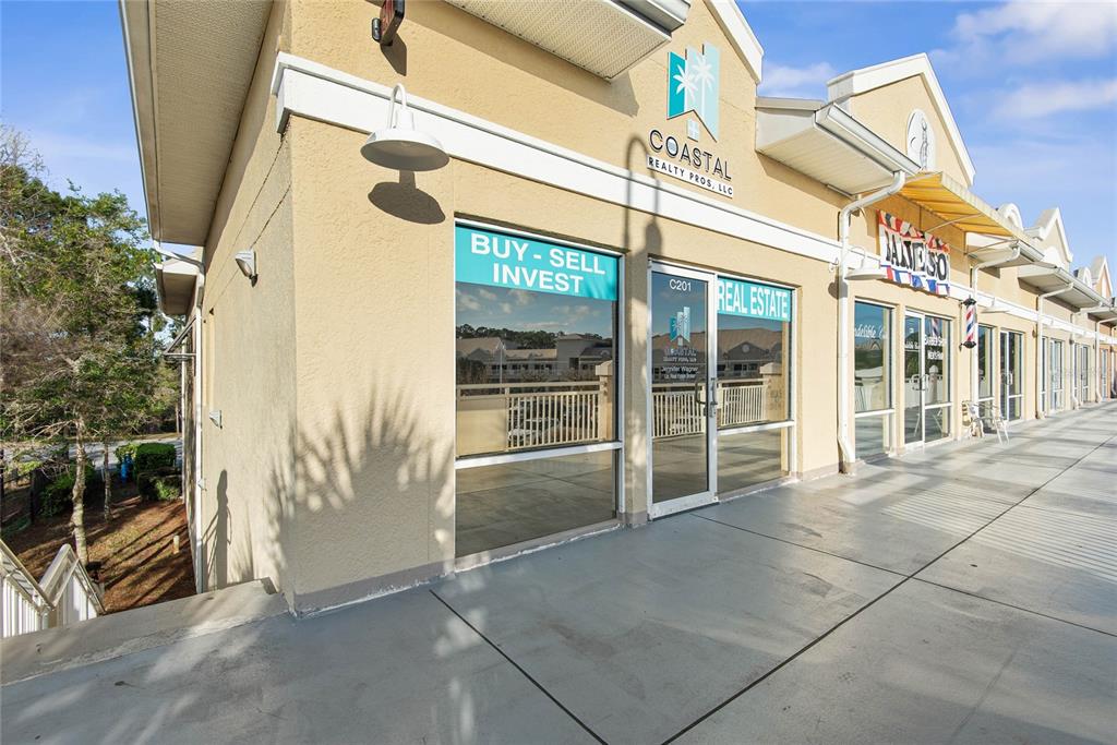 The exterior of a commercial building features a real estate office with large glass windows — 160 CYPRESS POINT PARKWAY UNIT C201 A, PALM COAST, FL