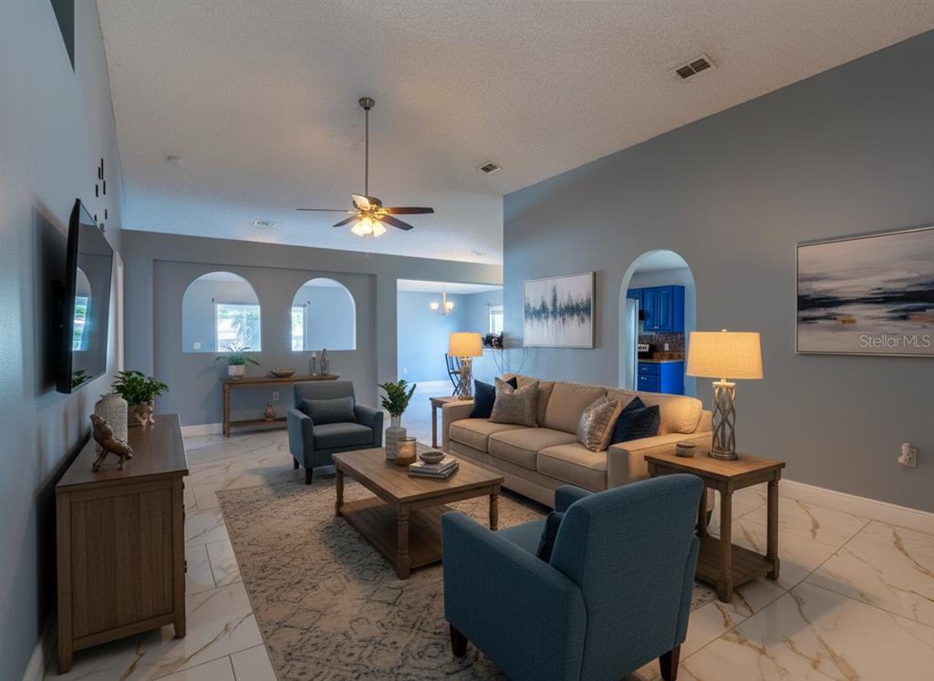 A living room with blue walls, tile floors, a beige sofa, and two blue armchairs — 12919 KINGS LAKE DRIVE, GIBSONTON, FL
