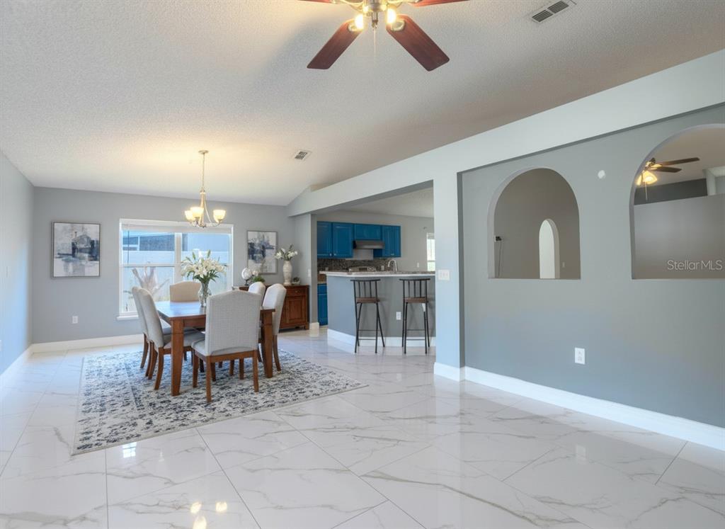 A dining area with a table and chairs sits adjacent to a kitchen with blue cabinets — 12919 KINGS LAKE DRIVE, GIBSONTON, FL