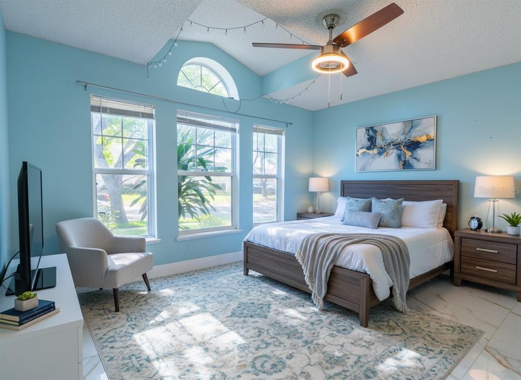 A light blue bedroom features a wooden bed, a ceiling fan, and three large windows — 12919 KINGS LAKE DRIVE, GIBSONTON, FL