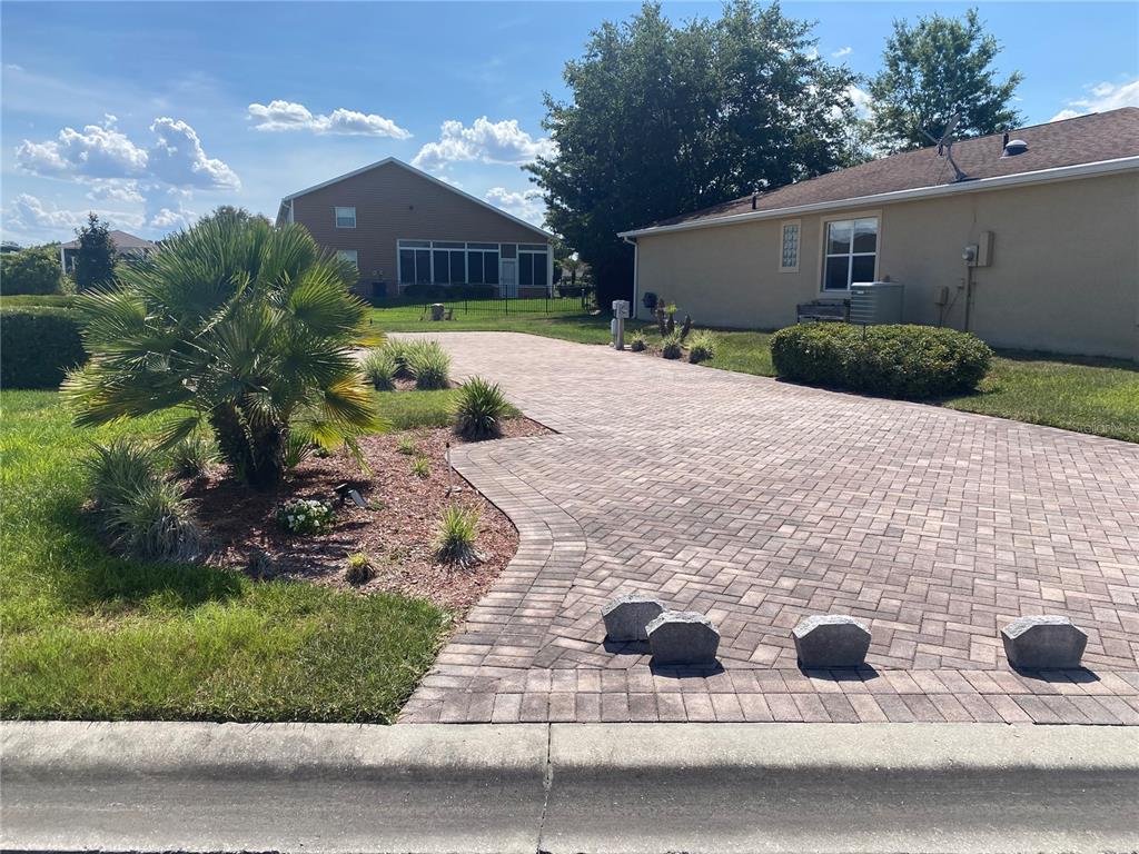 A paved driveway leads to a house with a palm tree and landscaping in the yard — 368 MOTORCOACH DRIVE S, POLK CITY, FL