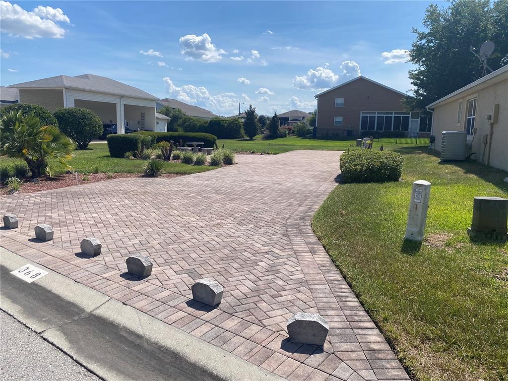 A paved driveway leads toward a house with a covered garage and surrounding lawn — 368 MOTORCOACH DRIVE S, POLK CITY, FL