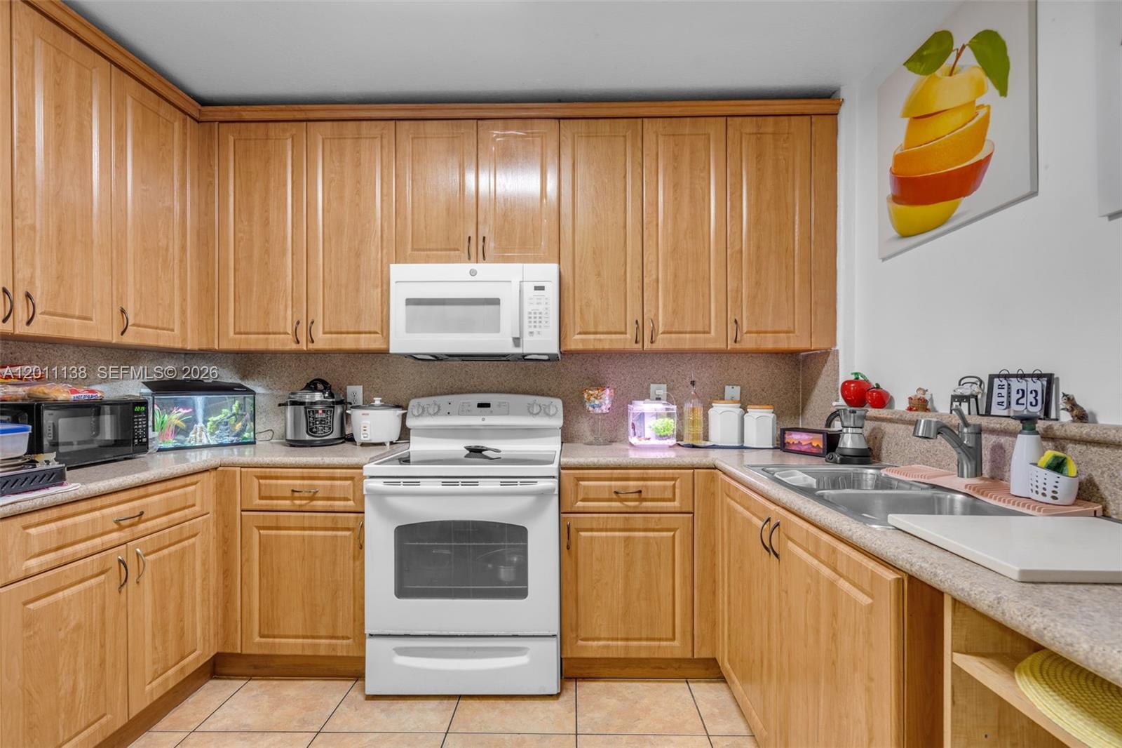 A kitchen features light wood cabinets, white appliances, and tan countertops — 8031 W 36th Ave # 1, Hialeah FL 33018, HIALEAH, FL