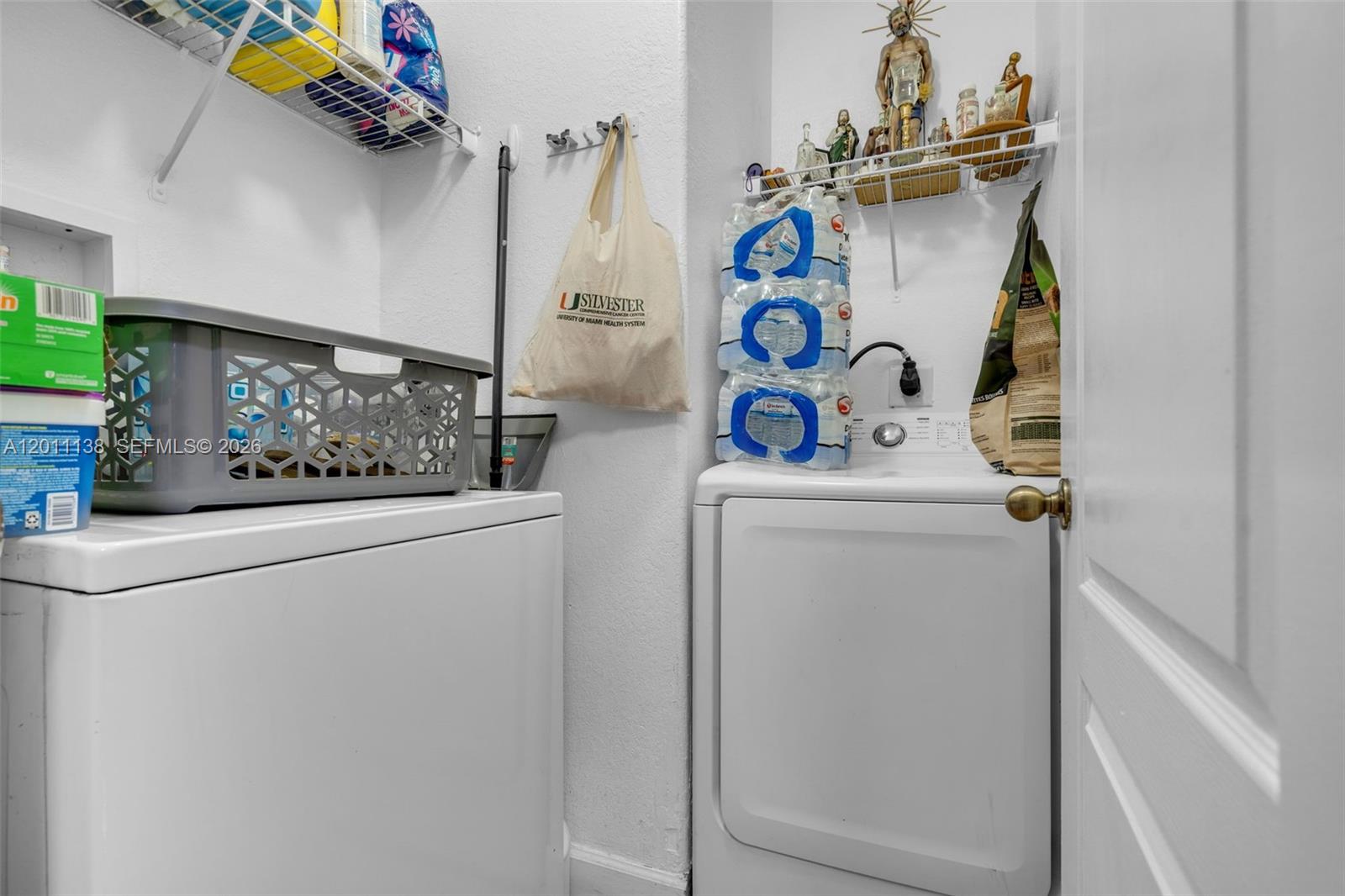 A laundry room features a washer and dryer with storage shelves and a hanging bag — 8031 W 36th Ave # 1, Hialeah FL 33018, HIALEAH, FL