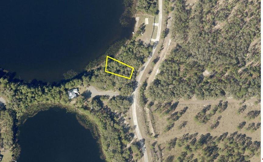 This aerial view shows a vacant, wooded lot outlined in yellow next to a lake — LOT 37 MALAUKA RAD, OCKLAWAHA, FL
