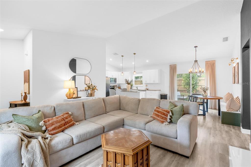 A living room with a large sectional sofa opens to a kitchen and dining area — 1755 15TH STREET, ORANGE CITY, FL