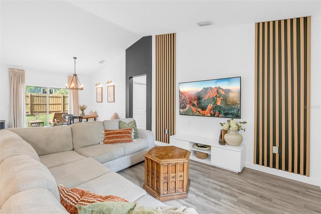 A living room features a sectional sofa, a television, and vertical wood slat wall accents — 1755 15TH STREET, ORANGE CITY, FL
