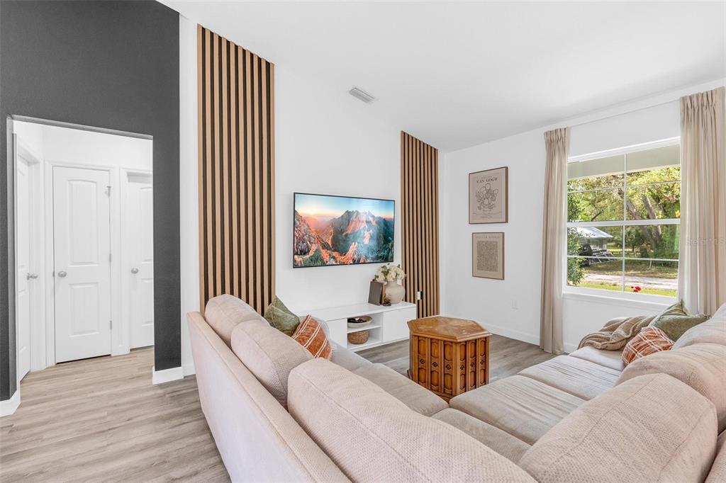 A living room features a sectional sofa, a wall-mounted television, and vertical wood slat accents — 1755 15TH STREET, ORANGE CITY, FL