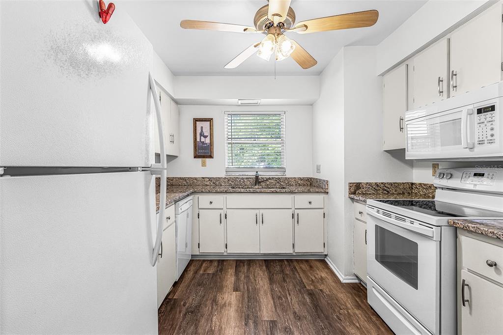 A kitchen with white cabinets, granite countertops, stainless steel appliances, and wood-look flooring — 4504 SE 6TH PLACE UNIT A+B, CAPE CORAL, FL