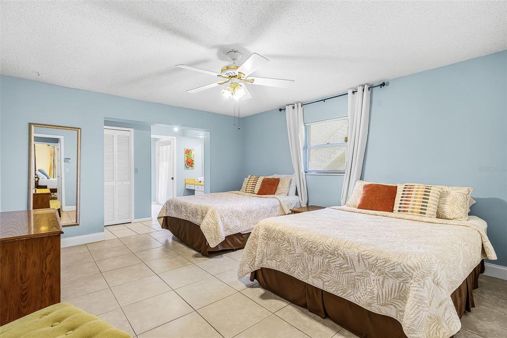 A bedroom features two beds, light blue walls, tile flooring, and a ceiling fan — 4504 SE 6TH PLACE UNIT A+B, CAPE CORAL, FL
