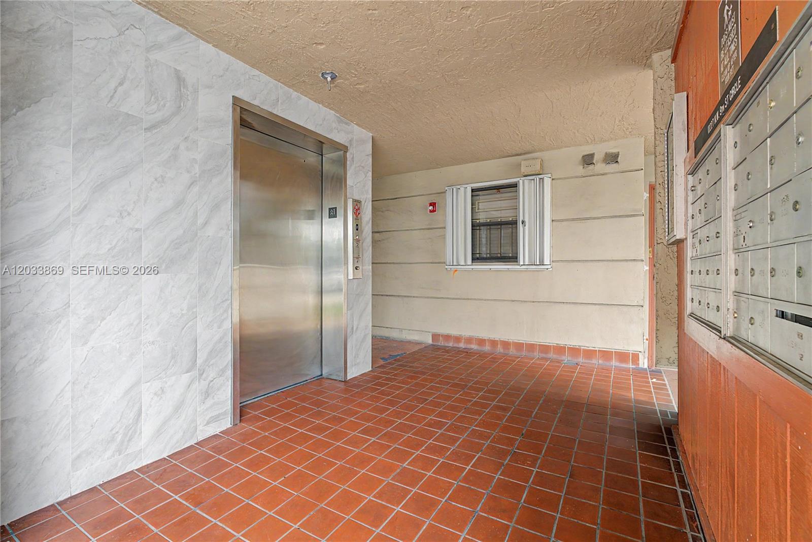 An elevator with marble-look tiling stands next to a wall of mailboxes and a window — 10227 NW 9th St Cir # 3, Miami FL 33172, MIAMI, FL