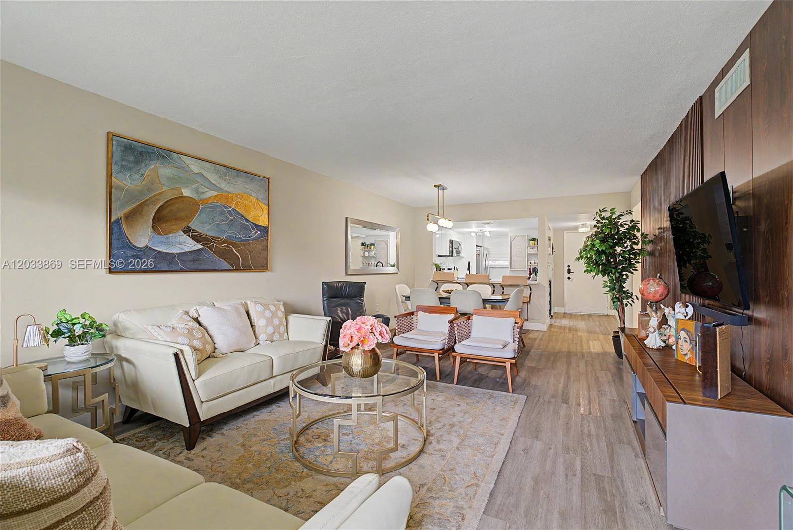 A living room features a white sofa, glass coffee table, wood-paneled wall, and dining area — 10227 NW 9th St Cir # 3, Miami FL 33172, MIAMI, FL