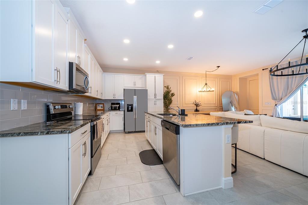 A kitchen with white cabinets, granite countertops, stainless steel appliances, and a central island — 1660 TROPICAL PALMS CIRCLE, KISSIMMEE, FL