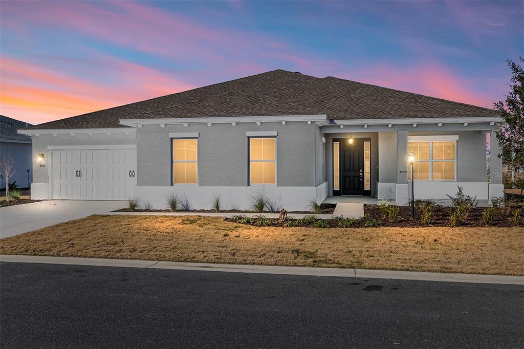 A single-story gray house with a white base, a two-car garage, and a sunset sky — 9918 SW 106TH CIRCLE, OCALA, FL