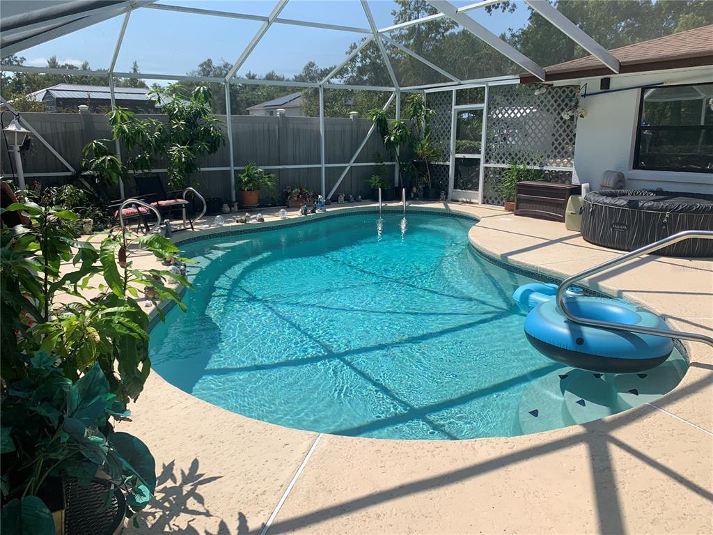 A screened-in swimming pool with a hot tub and patio area in a backyard — 4308 SW 139TH PLACE, OCALA, FL