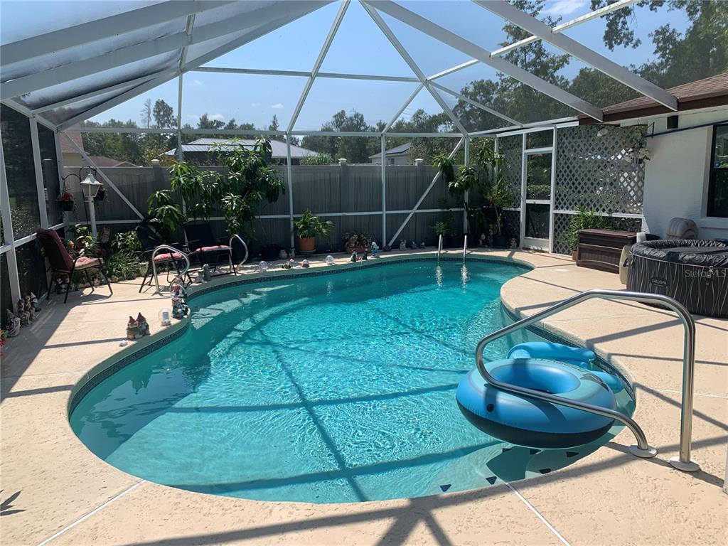 A screened-in backyard patio features a kidney-shaped swimming pool and a portable hot tub — 4308 SW 139TH PLACE, OCALA, FL